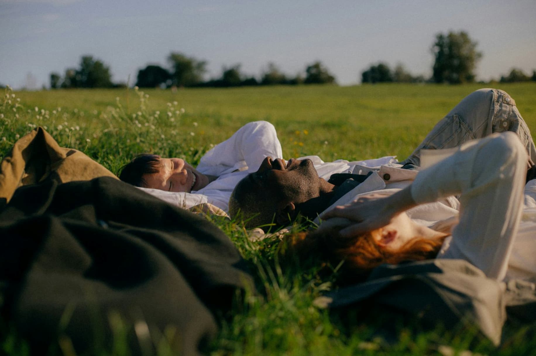Three friends resting together in a sunlit meadow
